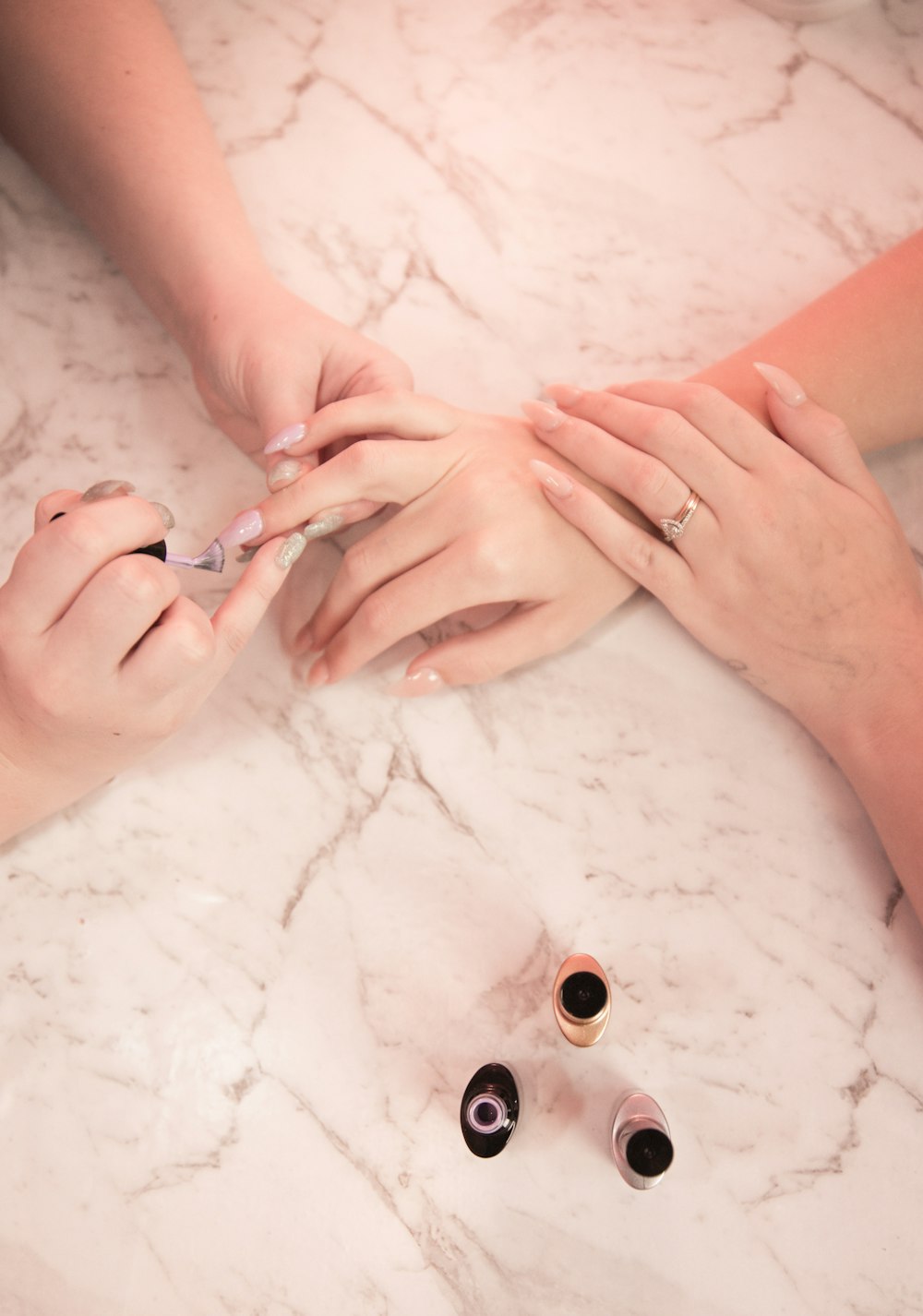 Technician painting a client's nails on a marble table